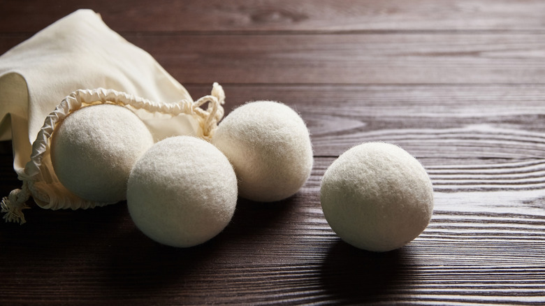 Four wool dryer balls on a wooden table with a bag