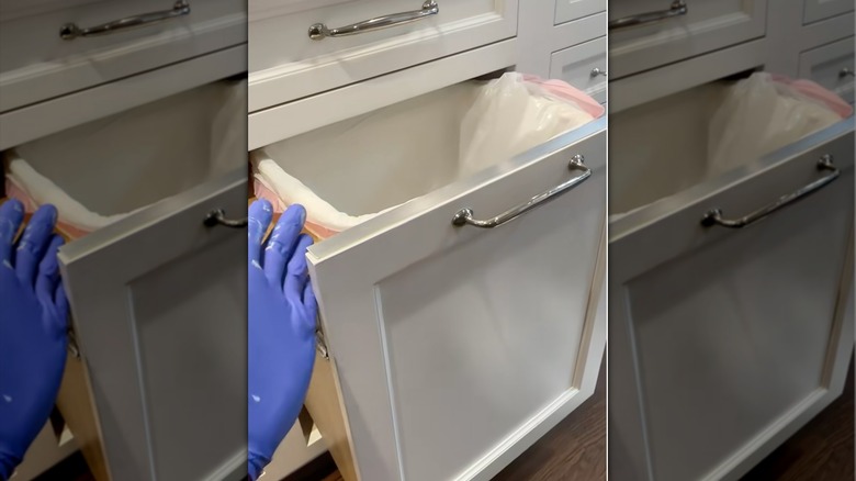A person wearing purple gloves shows off their newly-attached DIY aluminum trash cabinet edge.