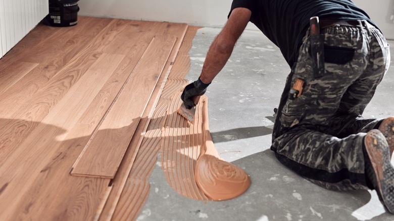 A carpenter spreads hardwood floor glue