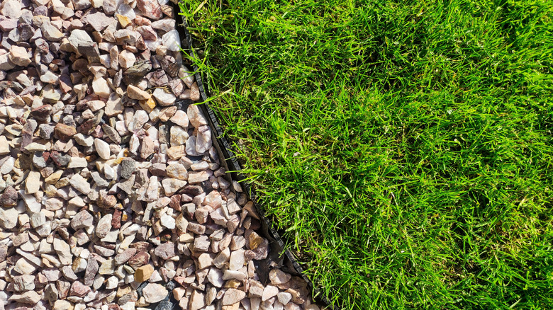 Grass lawn and gravel separated by a plastic edging