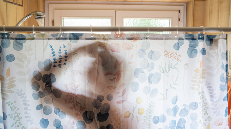person in the shower behind a shower curtain