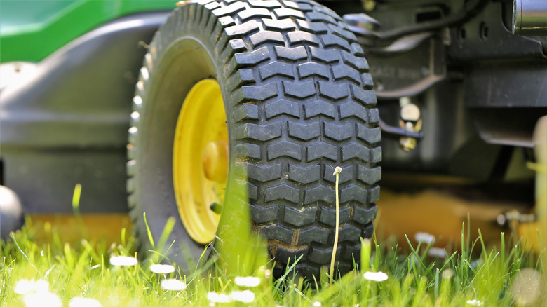 A close-up of a lawn mower tire on green grass