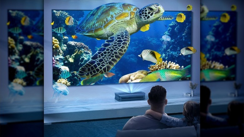 Man and child watching content on AWOL Vision Projector showing turtle underwater