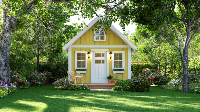 A small cottage-style home framed by a tree-lined small yard