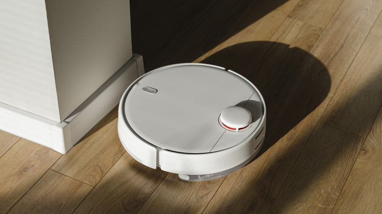 A white robot vacuum on a wood floor