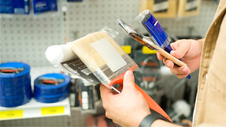 Close-up of a person holding several paintbrushes in a store
