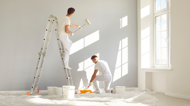 A team of professional painters, paint a room with a light grey shade.