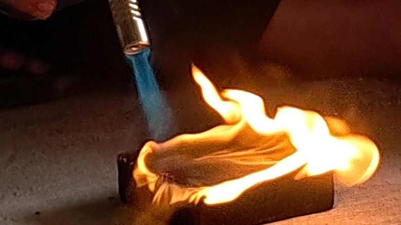A torch burns a wood surface to do a Shou Sugi Ban finish.
