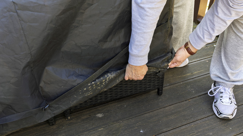 person trying to cover patio furniture