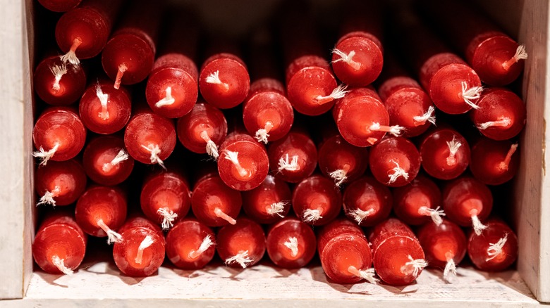 Red taper candles piled on top of each other in a crate.