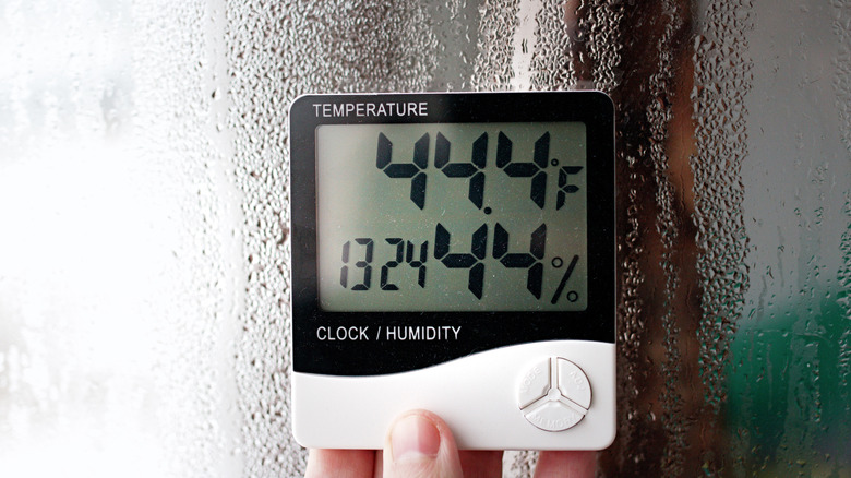 finger touching thermometer/hygrometer in home
