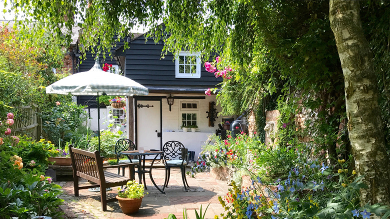 A lush backyard with a table, chairs, and umbrella and lots of vegitation