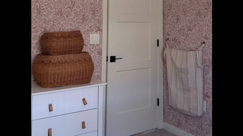 hanging laundry basket behind a door in a pink and white bedroom