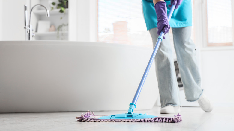 Woman mopping the floor of a bathroom