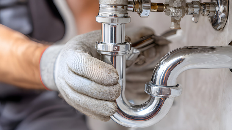 Person fixing piping below a sink