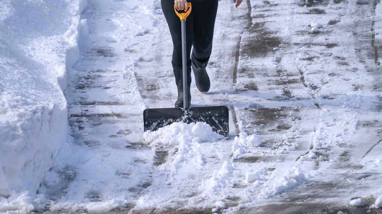 Person shoveling snow residual from a driveway