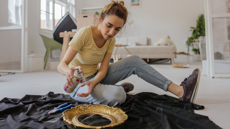 Woman spray painting vintage frame