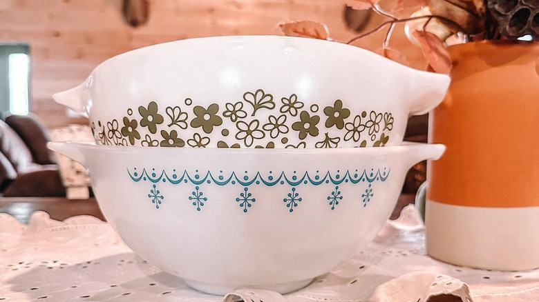 Stack of two Pyrex bowls, one with green and white flowers and one with blue and white snowflakes