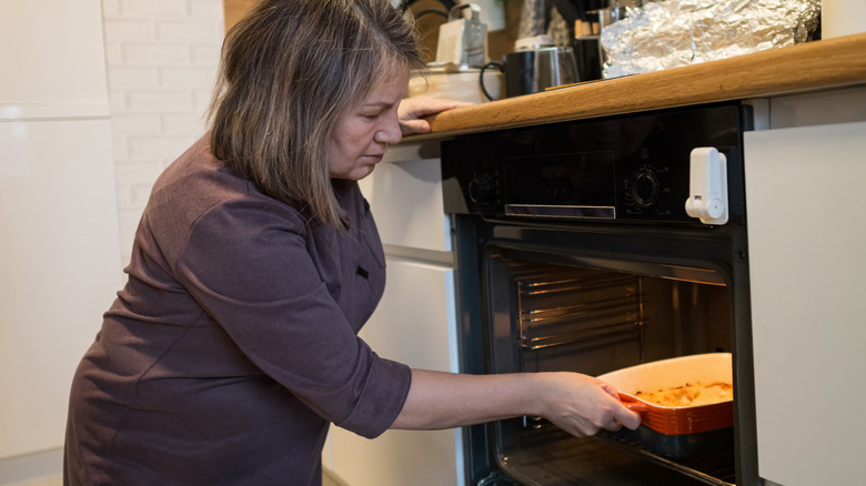 woman placing casserole dish in oven