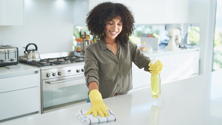 woman cleaning white stone countertop