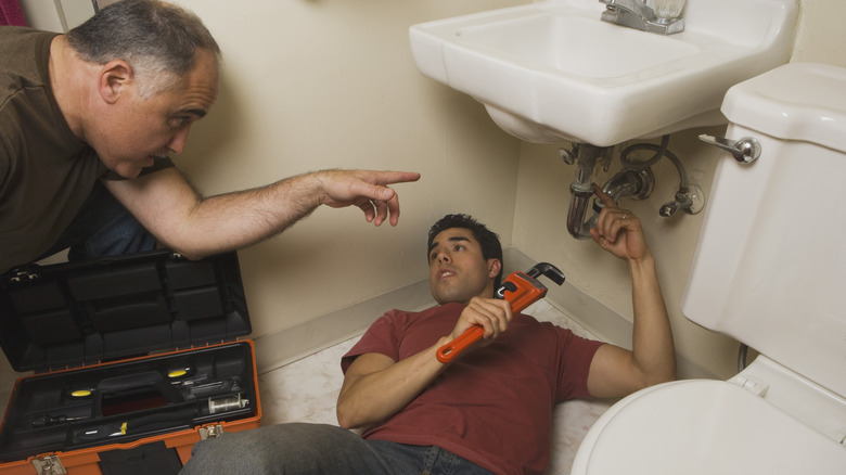 two plumbers working on sink