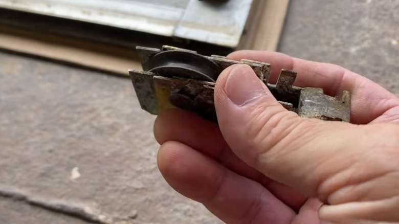 man holding old, dirty sliding glass door roller