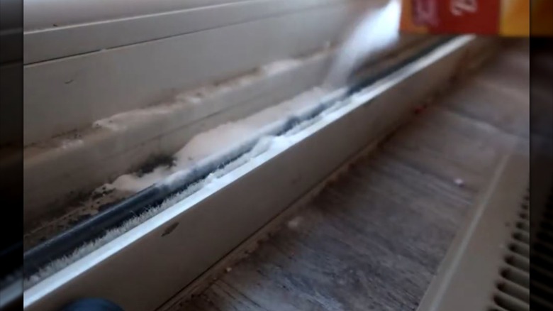 person cleaning sliding door track with baking soda