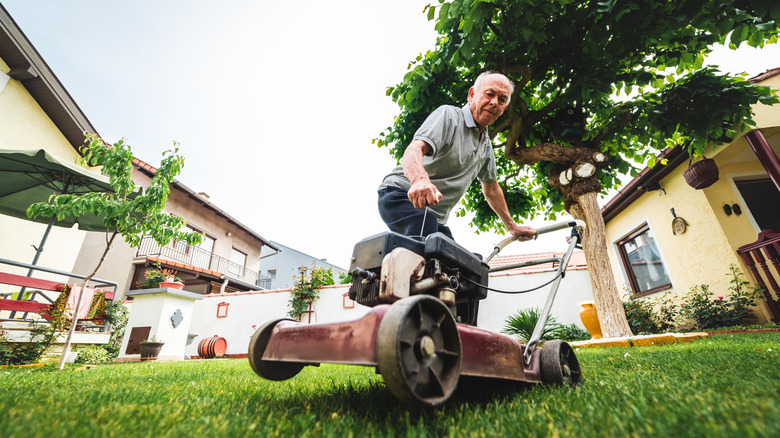 Man attempting to start a gas-powered lawn mower