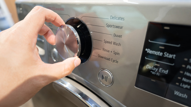Hand selecting a setting on a Samsung washing machine with options including Speed Wash, Rinse and Spin, Download Cycle, etc