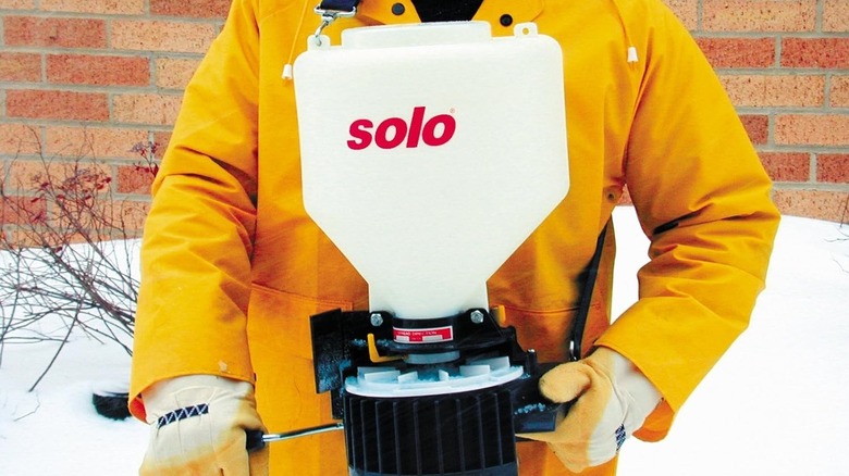 Person using a wearable spreader with ice melt
