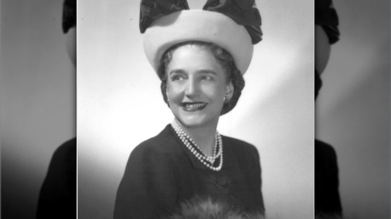 Dorothy Draper smiles for the camera, wearing a black dress and bow hat.