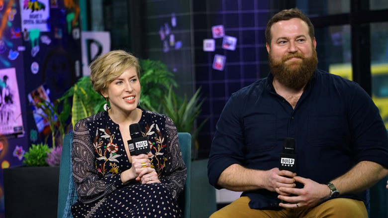 Erin Napier and Ben Napier sitting on a stage, smiling with mics in hand