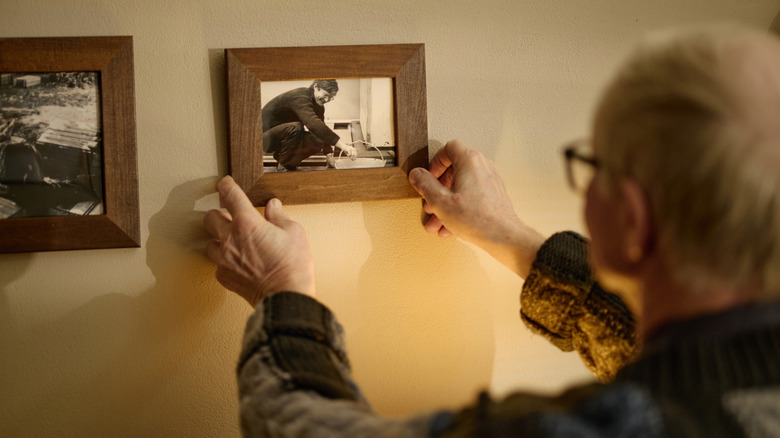 A man hanging up a sentimental black and white photo on a wall