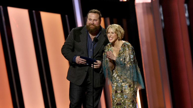 Erin Napier and Ben Napier in formalwear speaking on stage at an event