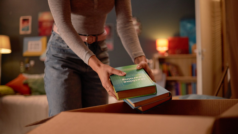 A person placing books in a box for donation
