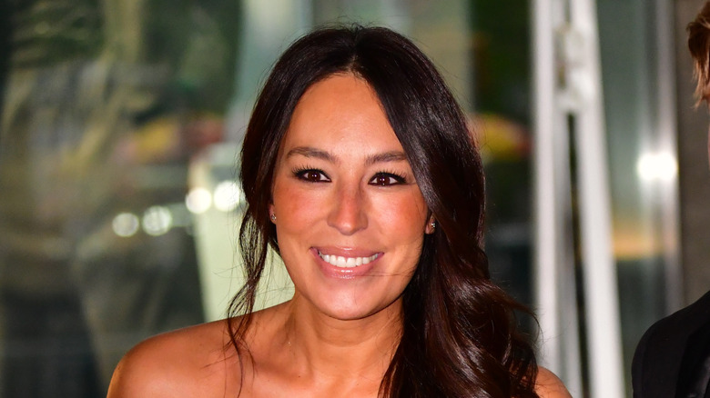 Joanna Gaines smiles with her hair to the side and glowy makeup