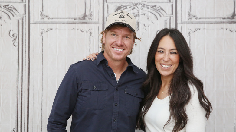 Joanna Gaines and her husband Chip smiling with arms around each other