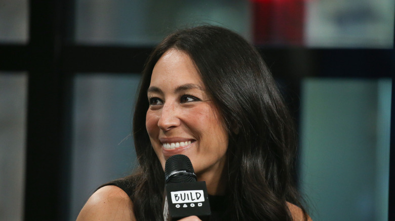 Joanna Gaines smiles while holding a microphone.