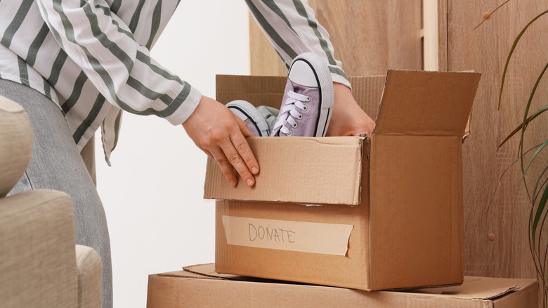 A person putting purple shoes in a box labeled 'donate'