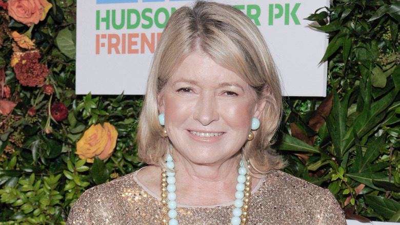 Martha Stewart smiles while wearing an evening gown in front of a floral display