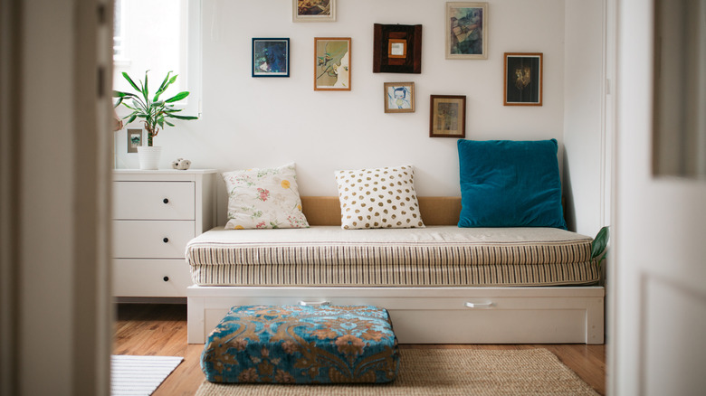 Room with day bed, vintage sofa cushion, and framed photos