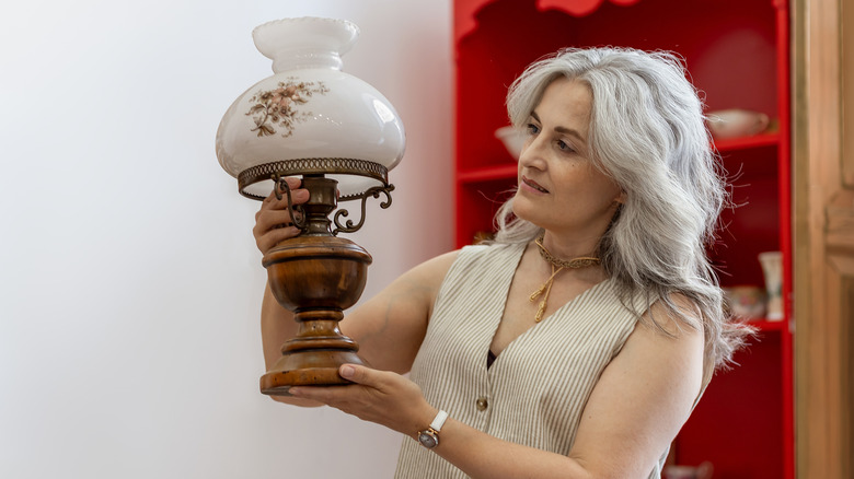 A woman holding and inspecting an antique lamp