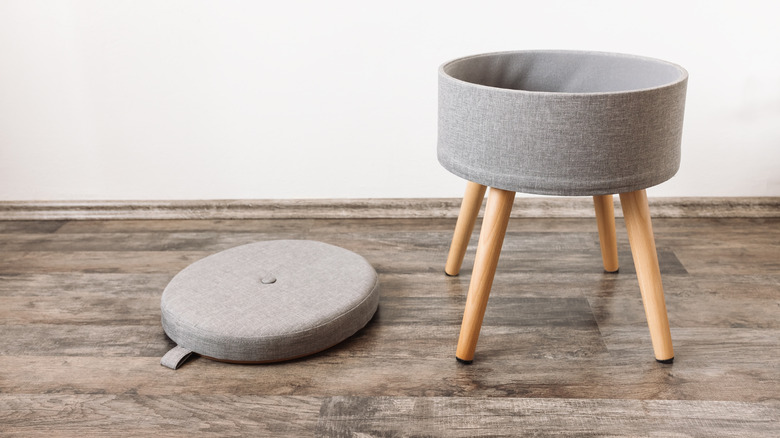 A small, round gray ottoman that opens into storage
