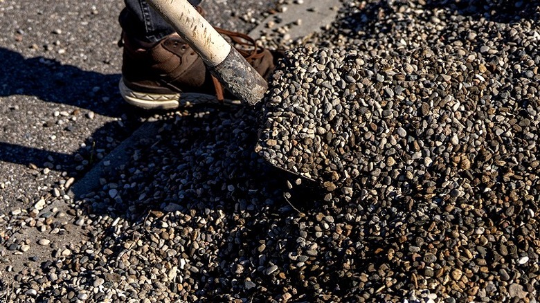 A person shoveling a gravel driveway