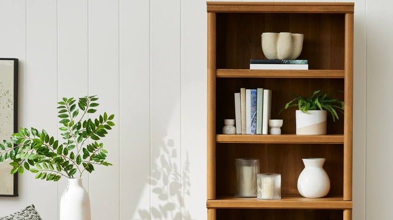 A brown bookshelf holding a few books and decor items