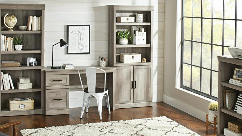 A rustic gray bookshelf with matching desk and shelves in a room