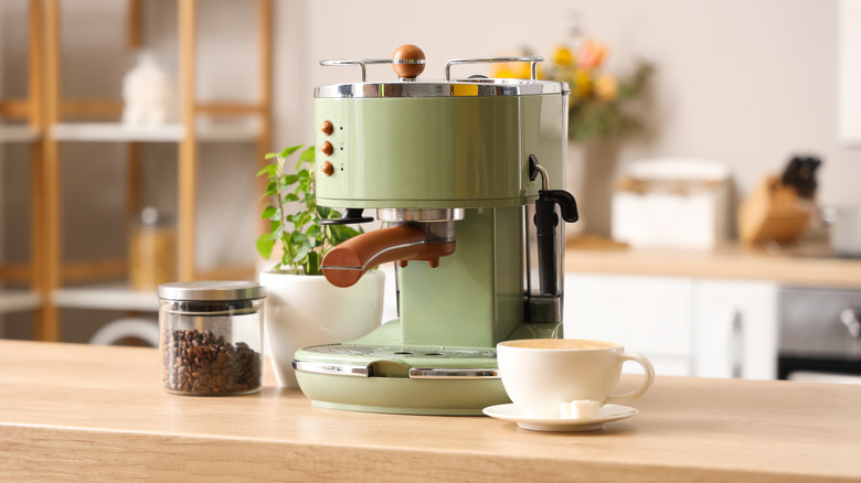 Modern retro-style coffee maker on home counter with coffee accessories