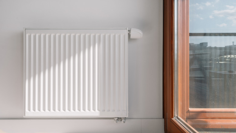 Electric heater mounted on home interior wall by window