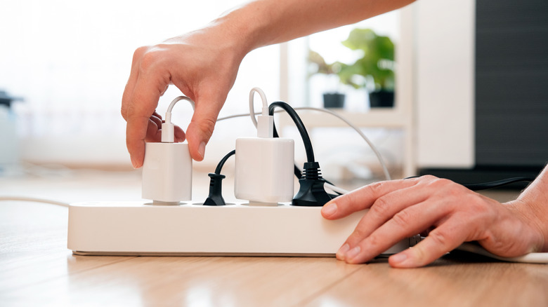 Hands plugging cords into a power strip