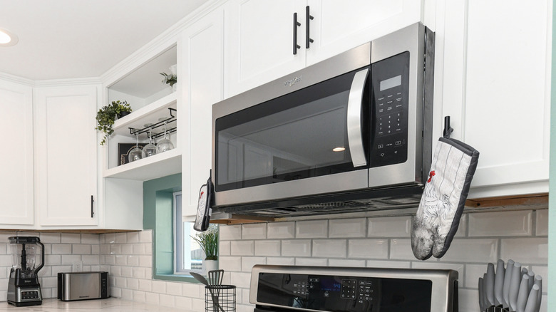 Hanging microwave oven in modern kitchen with glossy brick backsplash
